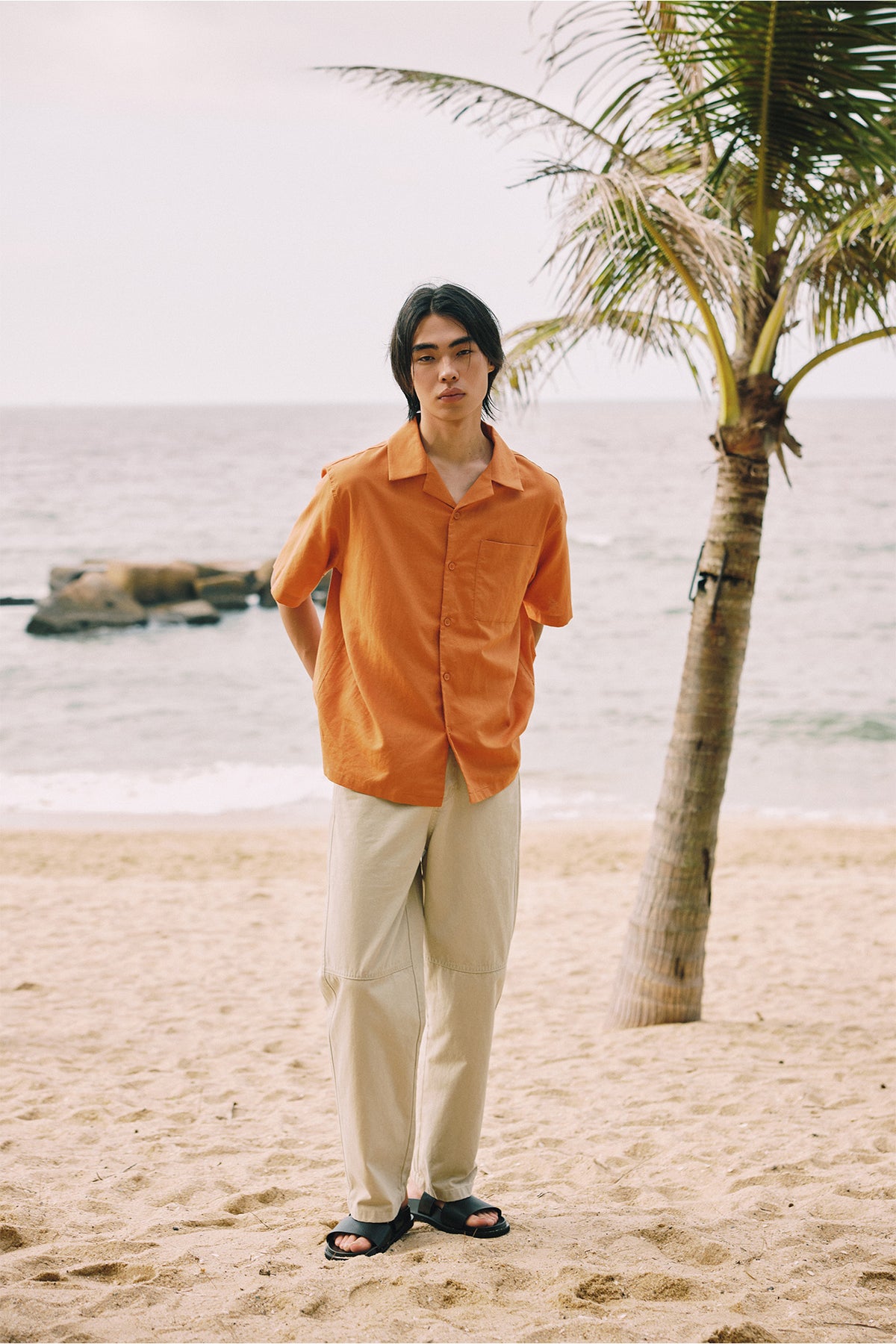 An open collar in washed orange, worn loose over a light trouser.